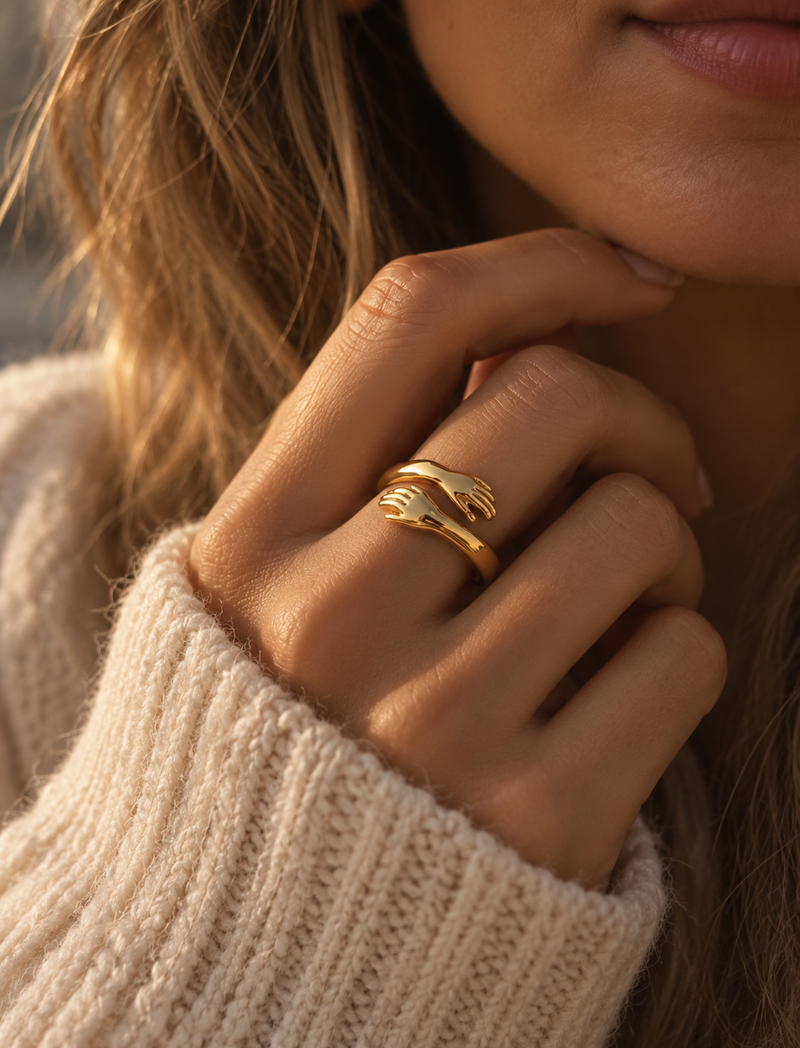 Närbild av Kram-ringen i guld till stickad tröja